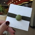 Detail of olive green matte bead elastic hair tie on a white presentation card - Green