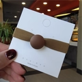 Detail of high-elasticity dark brown hair tie with matte ball on display card - Coffee