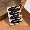 Set of four minimalist black non-marking hair clips on white card for styling - Black