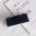 Set of 9 black spiral hair ties in a transparent box on a minimalist white fabric background - Solid Black