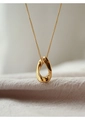 Dettaglio di una collana con ciondolo ovale dorato su sfondo di tessuto rosa testurizzato - Oro