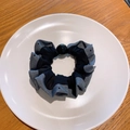 Gros plan d'un chouchou à pois et satin avec une grande perle noire sur une assiette blanche - Bleu Marine