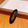 Elegant black oval acetate snap clip featuring a gold logo on a warm wood background - 8-Black
