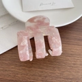 Pinza per capelli in acetato rosa marmorizzato con design geometrico su un tavolo - Rosa