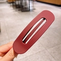 Minimalist large matte reddish-brown oval hair clip held by hand to show texture - Burgundy