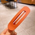 Minimalist matte orange oval hollow hair clip held by hand for a stylish daily look - Orange