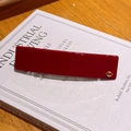 Minimalist deep red acetate hair clip with gold diamond accent on a book cover - Retro Copper