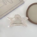 Iridescent hollow star hair claw clip in acetate material on a decorative tray - Yellow