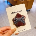 Star-shaped hair clip with brown plaid fabric and small grey velvet bow on display card - Plaid Star Style