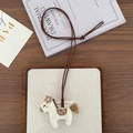 Detailed view of an embroidered fabric pony pendant necklace with tassel and brown cord - Floral White Horse