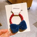 Elastic red beaded hair tie featuring a dark blue velvet bow on white card board - Red Ring Blue Bowtie
