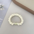Beige pleated scrunchie with green accent block on a neutral leather background - Yellow Hair Tie