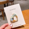 Blue and orange marbled acetate heart hair clip shown on display card in a cafe setting - Orange Green Marble (6043023950794)