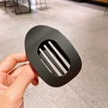 Pinza ovalada para el pelo en negro mate mostrada en mano para detalle de textura - Negro