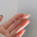 Minimalistische zilveren asymmetrische oorknop en oormanchet vastgehouden in de hand - Asymmetrische Oorknopjes met Schroefdraad / Zilver