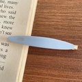 Elegante clip de acetato azul claro con logo dorado sobre fondo de libro antiguo - 1-Azul