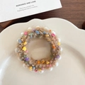 Brown plush scrunchie with colorful pom poms and white faux pearls in a warm, elegant setting - Khaki