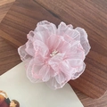 Rosa Organza-Blumen-Haarclip mit geschichteten Blütenblättern auf einem Holzhintergrund - Hellrosa