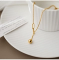 Macro shot of polished gold bead pendant and fine bead chain on a minimalist Y necklace - Adjustable Bead Style / Gold