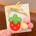 Détail d'un joli pendentif fraise sur un élastique à cheveux jaune pour enfants - Style Fraise