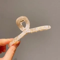 Minimalist marble cream acetate hair claw clip with cross design held by hand - Creamy Apricot