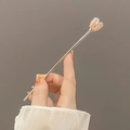 Close-up of golden tulip hair pin with pink floral detail held against a dark background - Pink