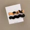 Detail von gewellten Haarklammern in Schildpattoptik und Schwarz mit goldener Aufschrift - Khaki & Schwarz