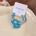Blue and green woven hair tie with embroidered blue flower on a ceramic display plate - Small Yellow Flower Style
