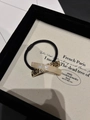 Elegant hair tie with gold textured metal and ivory resin accent on a black elastic band - White