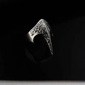 Macro detail of gothic eagle beak ring with floral carvings on polished black surface - US 8 / Silver