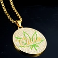 Vue macro du pendentif hip-hop doré avec motif feuille verte et cristaux brillants - Pendentif Rond Doré Feuille + 60cm