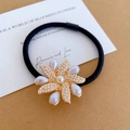 Elastic black hair tie with a premium pearl flower ornament and golden metal base - Windmill Pearl Style