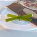 Classic olive green acetate bow hair clip with a glossy finish on a white ceramic plate - Green
