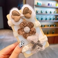 Detail von drei beigen Bären- und Blumen-Haargummis auf gelbem Display-Karton - Knopf weißer Bär 3-teiliges Set