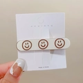 Sweet milk tea color hair clip featuring three brown smiley faces on a white metal base - Off White Small Smile