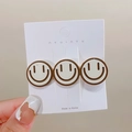 Cute milk tea colored duckbill hair clip with three beige smiley faces on a card - Off White Big Smile
