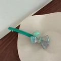 Detail view of the iridescent acetate bow hair clip in grass green on a white tray - Mint Green