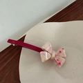 Detailed macro of a beige bow hair clip with red spots and France Handmade engraving - Rose Red