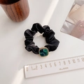 Macro detail of black satin scrunchie featuring a green marble resin accent and gold trim - Green