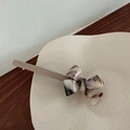 Eleganter Haarclip mit weiß-brauner Marmor-Azetat-Schleife auf matter Oberfläche - Khaki Stil 1