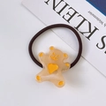 Detail of cute bear charm on elastic hair tie with yellow heart and paw prints - Beige