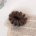 Elastico per capelli a spirale in maglia marrone scuro su pagina di libro vintage - Marrone