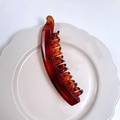 Matte amber tortoiseshell banana hair clip in a white ceramic dish for hair styling - Glossy Tortoiseshell