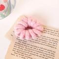 Chouchou spirale en peluche rose avec texture tricotée douce sur pages de livre ancien - Rose