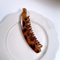 Classic tortoiseshell pattern banana hair clip with secure teeth on a white ceramic plate - Dark Leopard