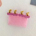 Pink girl's hair side comb featuring four purple cherry ornaments on a white textured surface - Rose Cherry