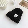 Thick black cable knit beanie with a stylish white decorative fashion label for women - Black