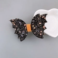 Halloween black bat hair clip with orange and purple sequins on a decorative white plate - Black Wings