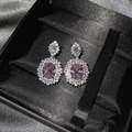 Detaillierte Nahaufnahme luxuriöser Silber-Ohrhänger mit ovalen rosa Edelsteinen und Halo - Kupfer / Rosa Zirkonia Ohrstecker