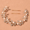 Dettaglio di un tralcio per capelli da sposa dorato con perle bianche e strass su superficie - TS265 / Oro